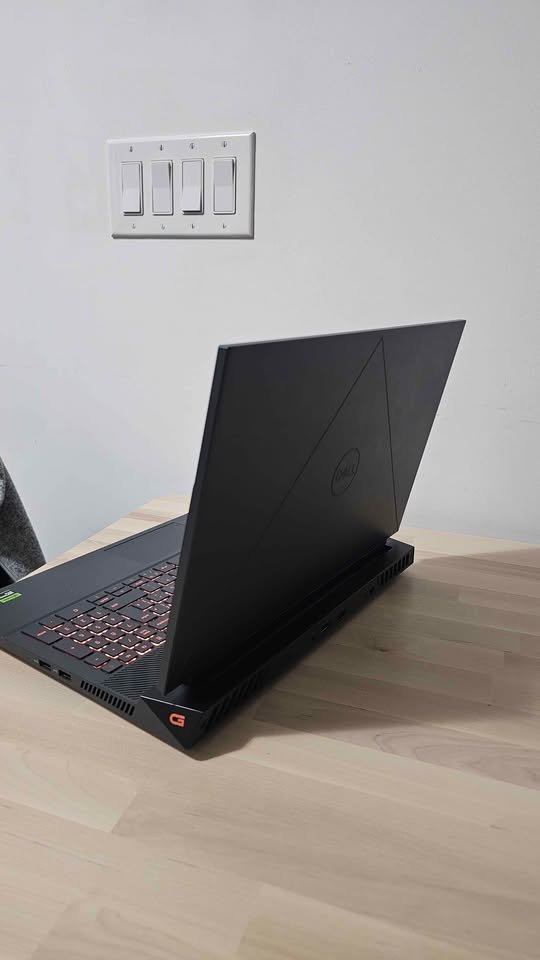 Dell G15-5530 gaming laptop rear side angle showing lid design, cooling vents, and red backlit keyboard